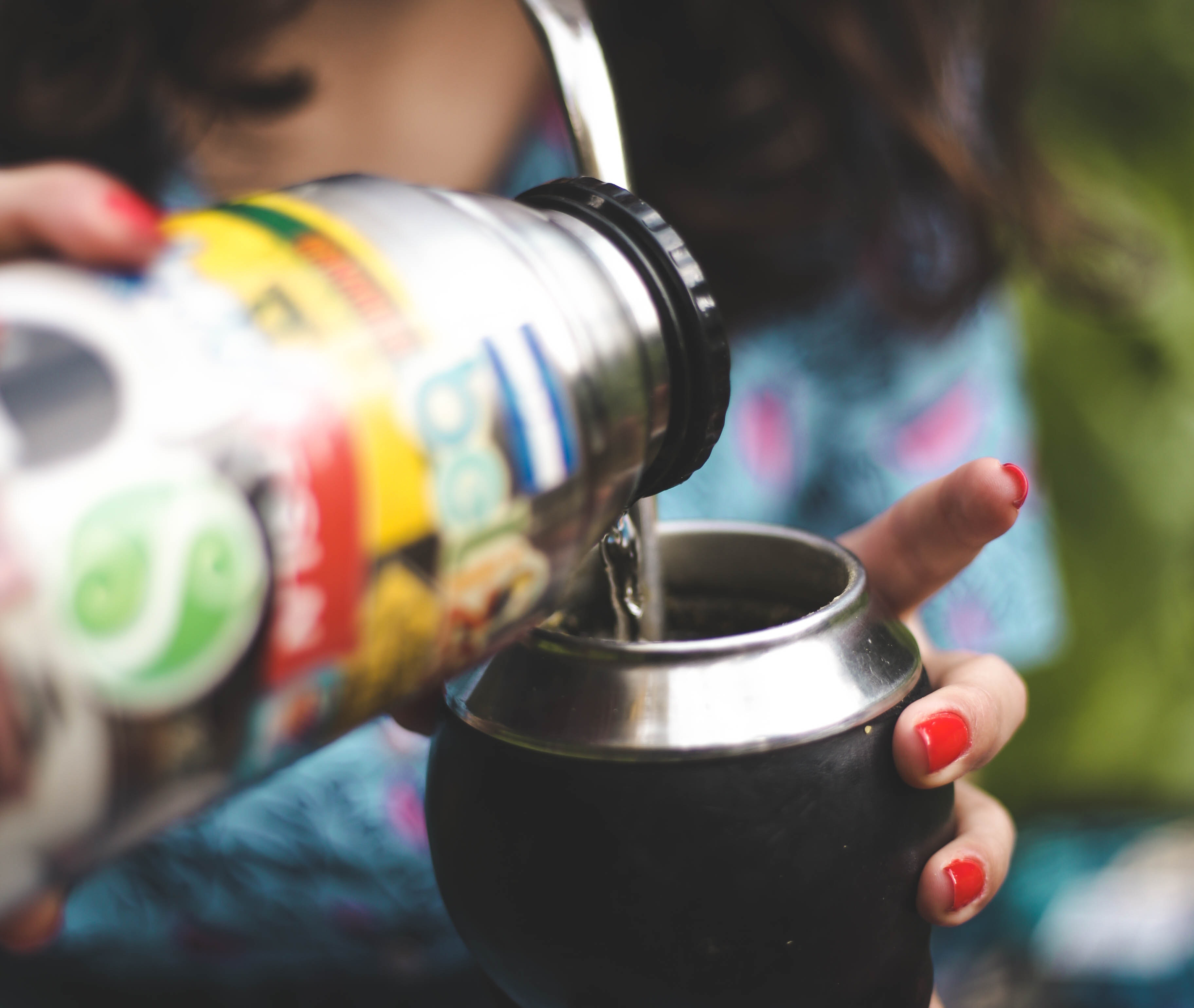 Image of a Person pouring water from thermos on yerba mate